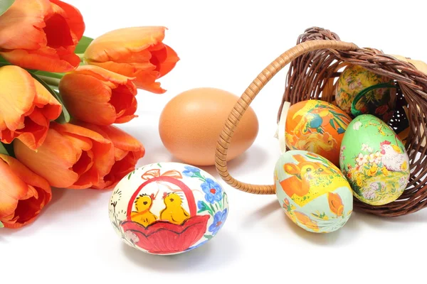 Easter eggs in overturned basket and fresh egg with tulips — Stock Photo, Image