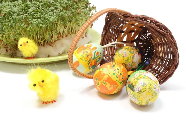 Ovos de Páscoa em cesta de vime derrubada e agrião verde — Fotografia de Stock