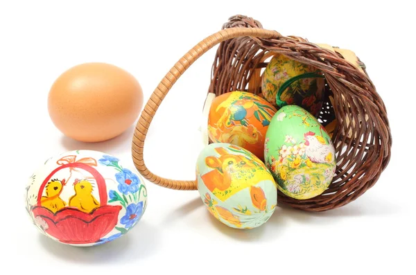 Colorful Easter eggs in overturned wicker basket and fresh egg — Stock Photo, Image