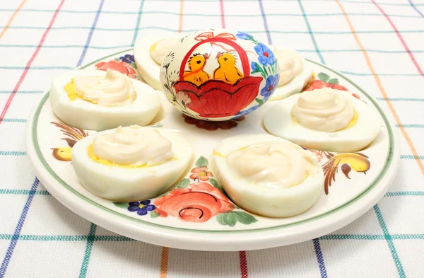 Půlky vajec s majonézou a malované vajíčko na barevné desky — Stock fotografie
