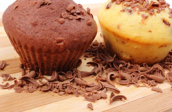 Fresh baked muffins and grated chocolate on wooden cutting board — Stock Photo, Image