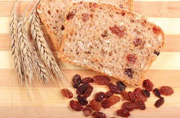 Fresh baked bread, ears of wheat and raisins — Stock Photo, Image