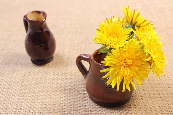 Yellow flowers of dandelion in brown vase