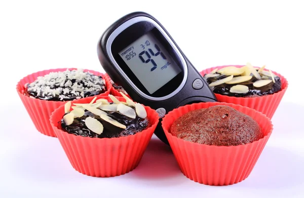 Glucometer and chocolate muffins in red cups — Stock Photo, Image