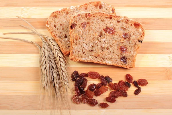 Fresh baked bread, ears of wheat and raisins — Stock Photo, Image