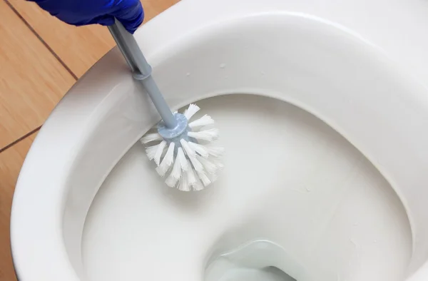 Mão de mulher em luva azul limpeza vaso sanitário — Fotografia de Stock