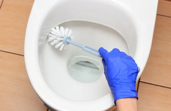 Mão de mulher em luva azul limpeza vaso sanitário — Fotografia de Stock