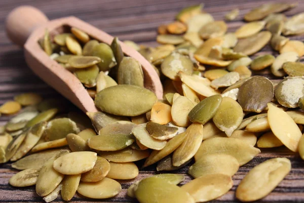 Semi di zucca con cucchiaio su sfondo di legno — Foto Stock