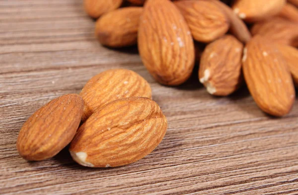 Heap of almonds on wooden background — Stock Photo, Image