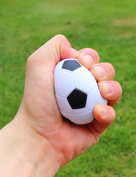 Pequeña bola de estrés en la mano sobre el fondo de hierba — Foto de Stock