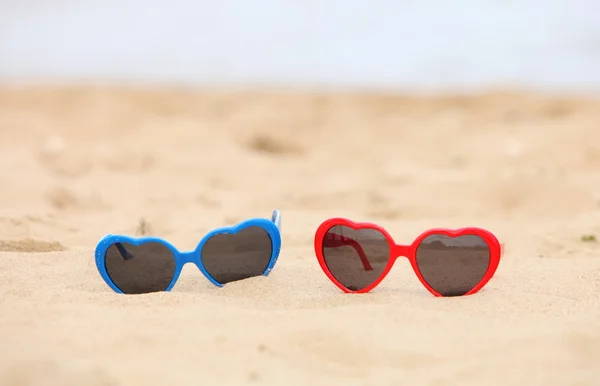 Kum üzerinde kalp şeklinde renkli Güneş gözlükleri — Stok fotoğraf