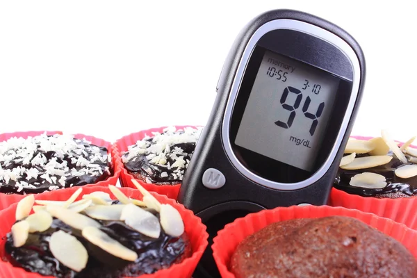 Glucometer and chocolate muffins in red cups — Stock Photo, Image