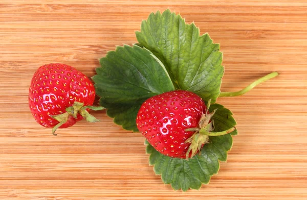 Strawberry with leaves on wooden surface — Stock Photo, Image