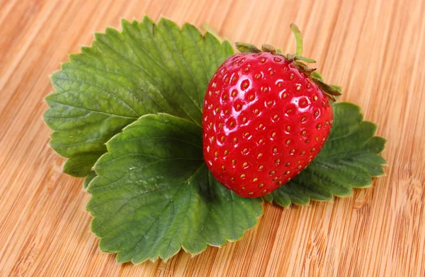 Strawberry with leaves on wooden surface — Stock Photo, Image