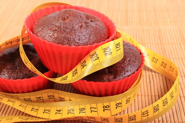 Schokoladenmuffins in roten Tassen und Maßband — Stockfoto