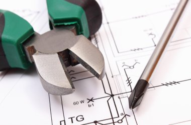 Metal pliers and screwdriver on electrical construction drawing of house