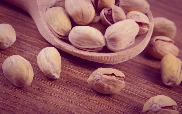 Foto d'epoca, Pistacchi con cucchiaio sul tavolo di legno, alimentazione sana — Foto Stock