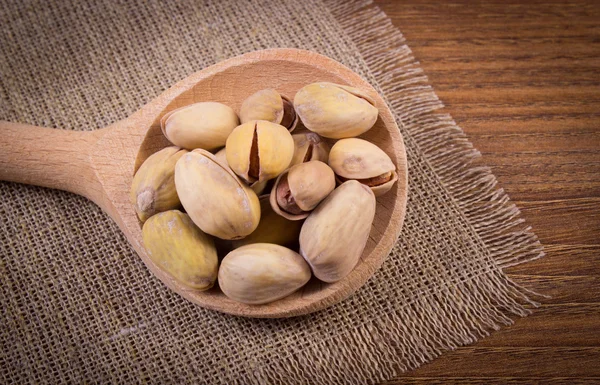 Zdjęcia archiwalne, orzechy pistacjowe z łyżką na drewnianym stole, zdrowe jedzenie — Zdjęcie stockowe