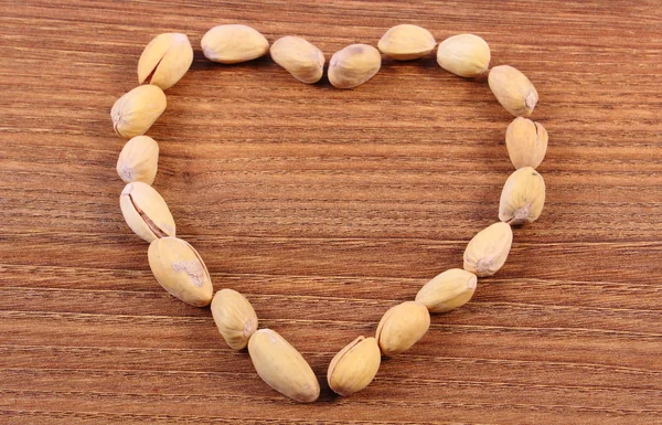 Herz aus Pistazienkernen auf Holztisch, gesunde Ernährung — Stockfoto