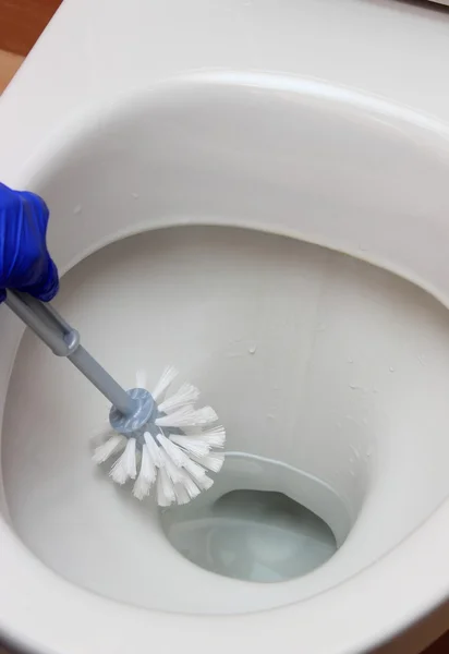 Hand van vrouw in blauwe handschoen reiniging van de toiletpot — Stockfoto