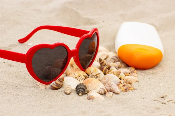 Seasonal concept, heap of shells, sunglasses and sun lotion — Stock Photo, Image