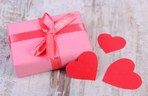 Regalo envuelto para cumpleaños, San Valentín u otra celebración y corazones rojos — Foto de Stock