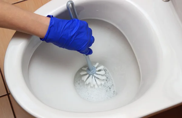 Mão de mulher em luva azul limpeza vaso sanitário — Fotografia de Stock