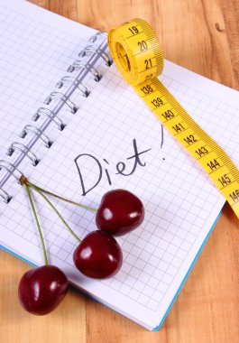 Cherry and centimeter with notebook, slimming and healthy food