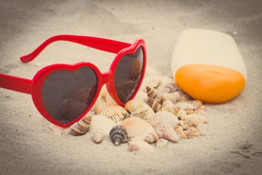 Vintage photo, Seasonal concept, heap of shells, sunglasses and sun lotion