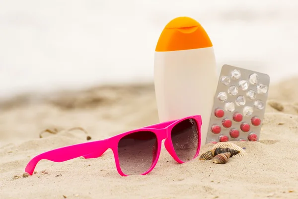 Pink sunglasses, shells, lotion and pills of vitamin A, seasonal concept — Stok fotoğraf