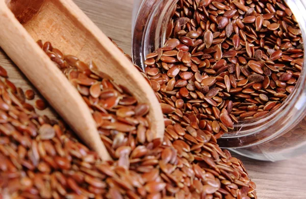 Linseed spilling out of jar on wooden background — Stock Photo, Image