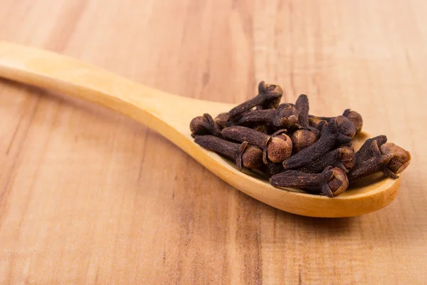 Nelkenhaufen mit Holzlöffel auf dem Tisch, Würze zum Kochen — Stockfoto