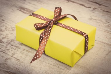 Vintage photo, Yellow gift for Christmas or other celebration on wooden plank