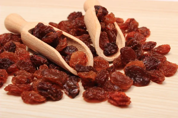 Braune Rosinen mit Löffel auf Holztisch, gesunde Ernährung — Stockfoto