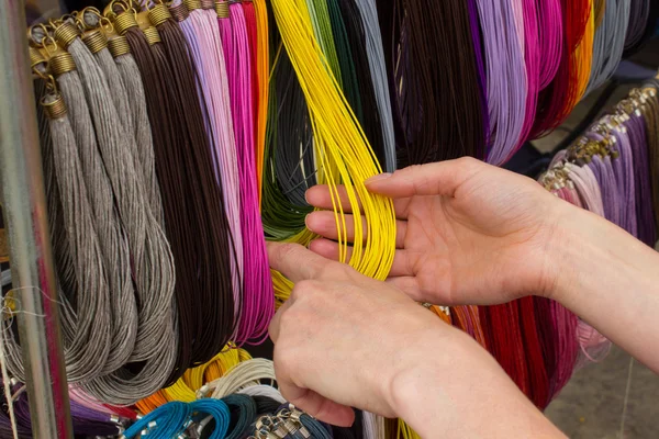 Mano de mujer con collar de colores en el puesto en el bazar —  Fotos de Stock