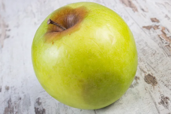 Zepsute jabłko na stary drewniany stół biały — Zdjęcie stockowe