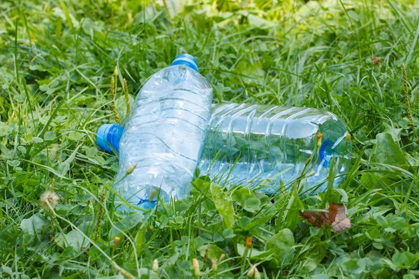 Plastic flessen mineraalwater op gras in park, bezaaid van milieu — Stockfoto