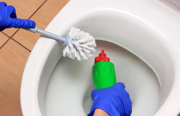 Mão de mulher em luva azul limpeza vaso sanitário — Fotografia de Stock