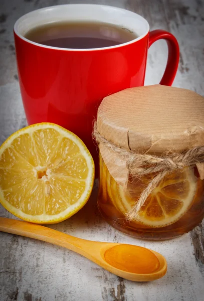 Lemon with honey and cup of tea on wooden table, healthy nutrition — ストック写真