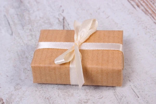 Wrapped gift for Christmas or other celebration on old wooden background — Stock fotografie