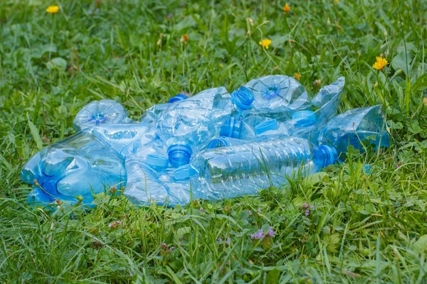Garrafas de plástico e tampas de garrafa na grama no parque, lixo do meio ambiente — Fotografia de Stock