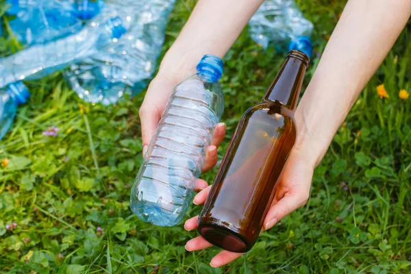 Plastic and glass bottle in hand of woman, littering of environment — Stock Photo, Image