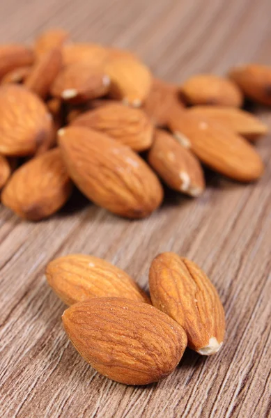 Heap of almonds on wooden background — Stock Photo, Image