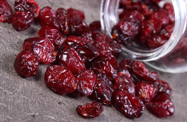 Cranberries spilling out of glass jar on concrete — Stock Photo, Image