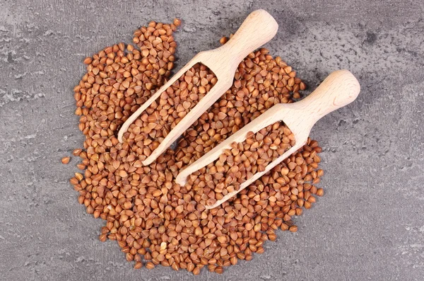 Buckwheat groats with spoon on cement structure — Stock Photo, Image