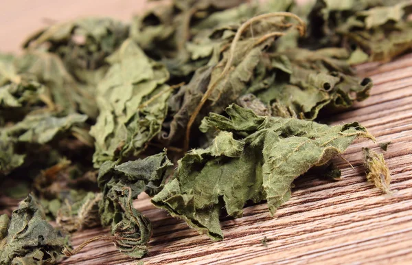 Heap of dried nettle on wooden surface — Stock Photo, Image