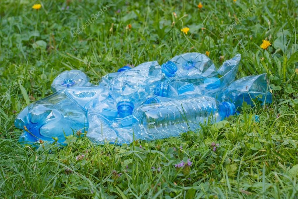 Plastic bottles and bottle caps on grass in park littering of