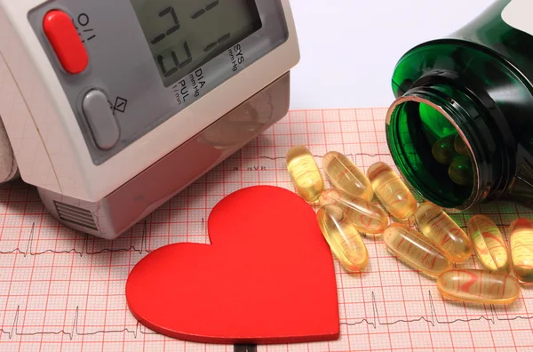 Heart shape, blood pressure monitor and tablets on electrocardiogram — Stock Photo, Image