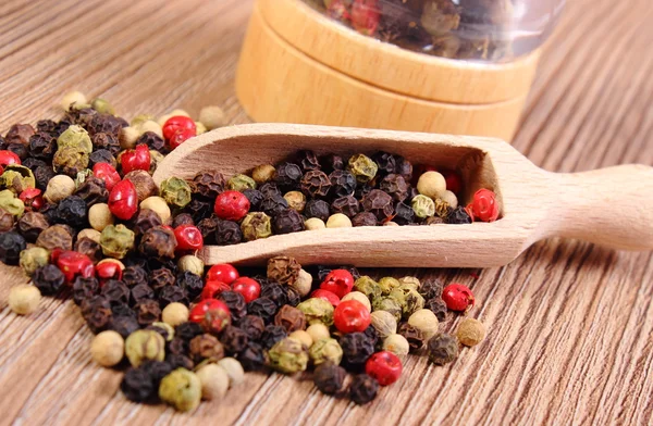 Pepper with spoon and mill on wooden background — Stok fotoğraf