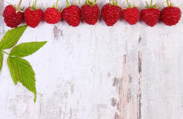 Fresh raspberries with leaf and copy space for text on old wooden background — ストック写真